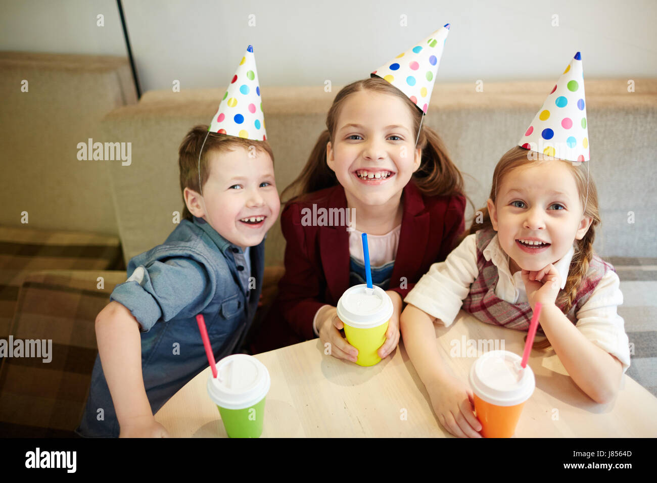 Adorable niños en cumpleaños caps mirando a la cámara Foto de stock