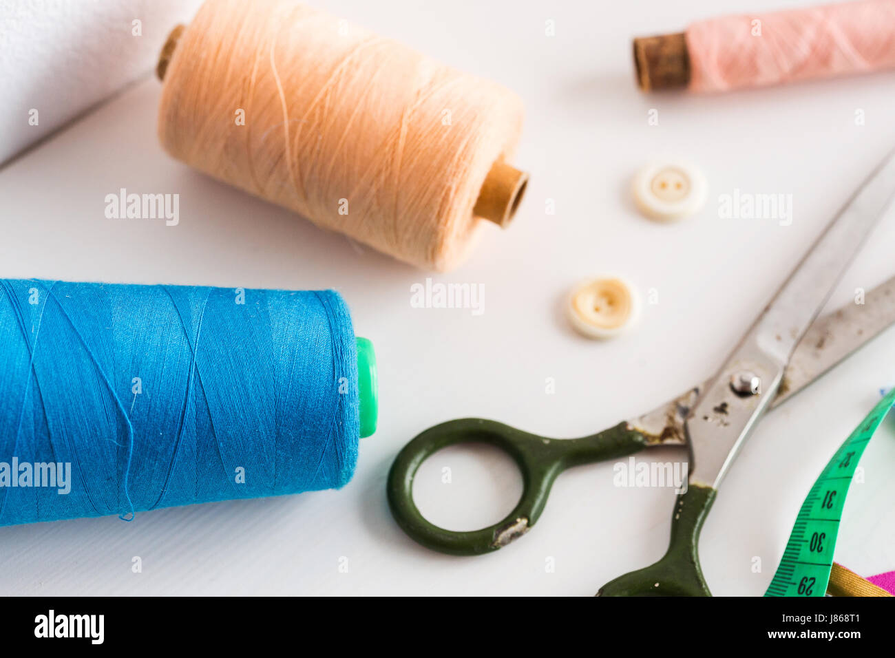 Herramientas de costura, patchwork, costura y moda - Concepto de cerca en blanco en el escritorio Studio, los carretes de hilo de colores, medidor, botones, muchos trabajaban tijeras, equipo principal de costura. Foto de stock