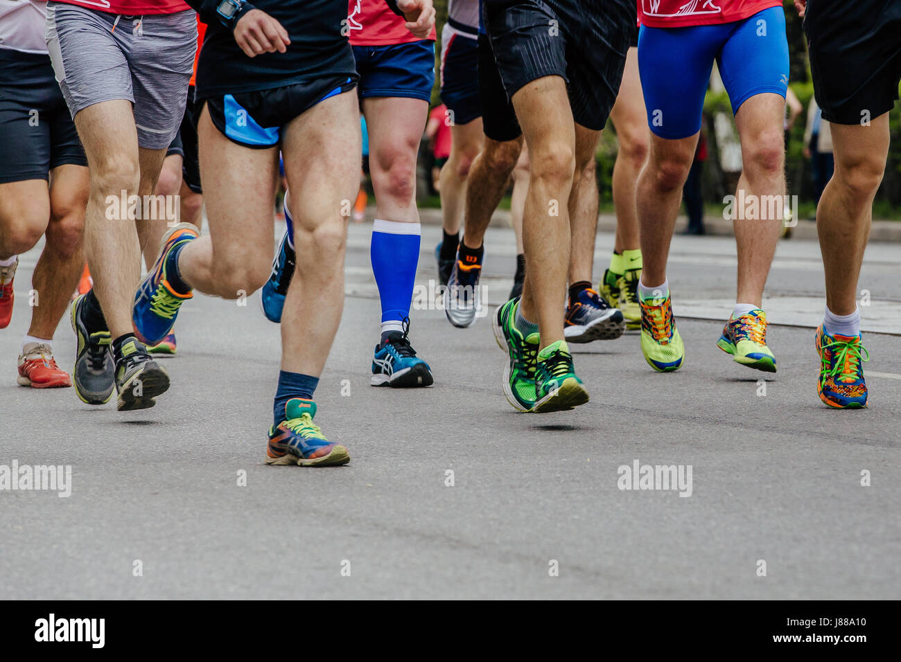 Piernas hombres corredores corriendo por la calle zapata en la media maratón de la ciudad Foto de stock
