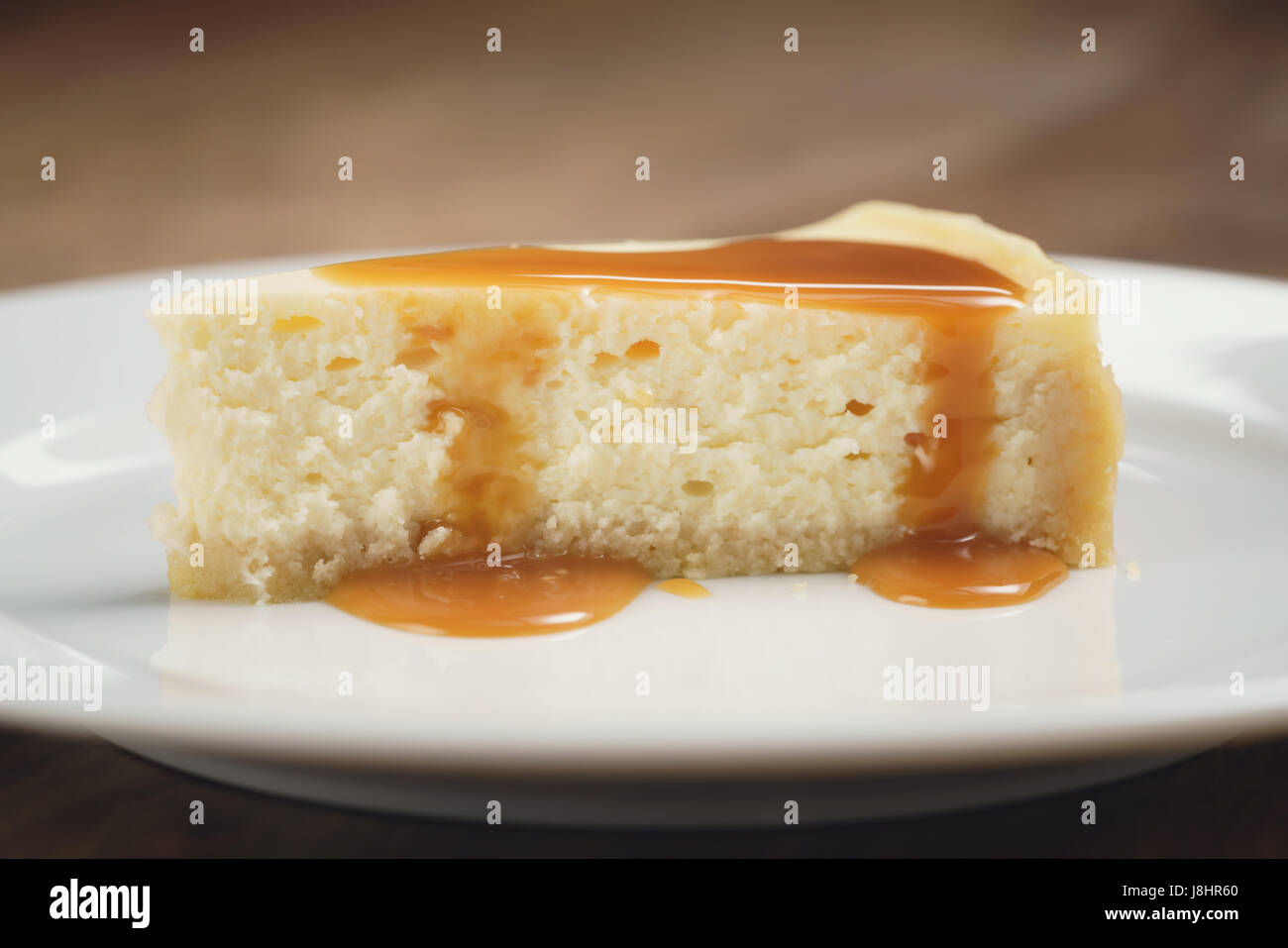 Salsa de caramelo Verter sobre la tarta de queso en la placa closeup Foto de stock