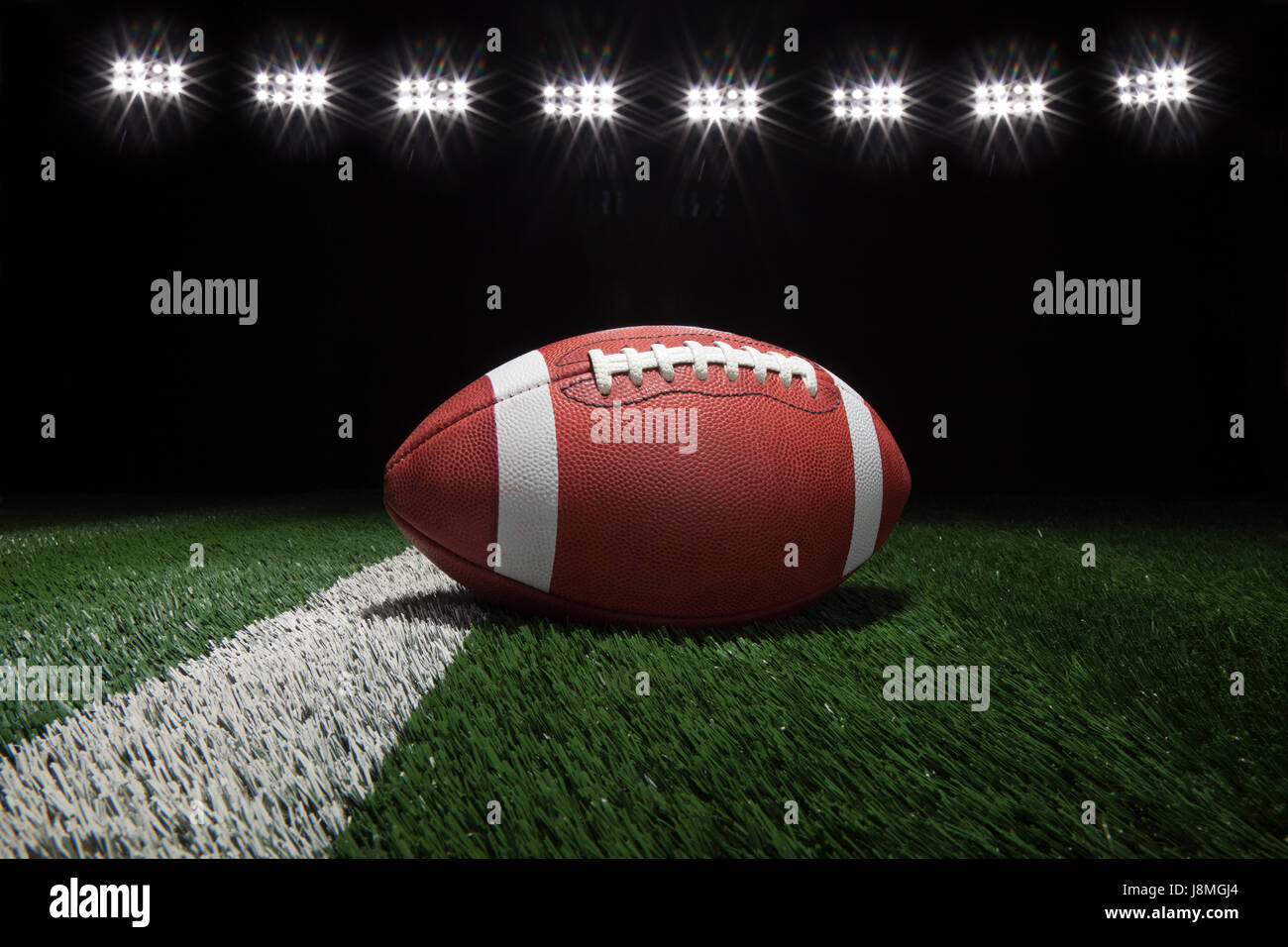 Ángulo de visión baja de college football en un patio de estilo de línea de un campo de fútbol bajo las luces del estadio Foto de stock