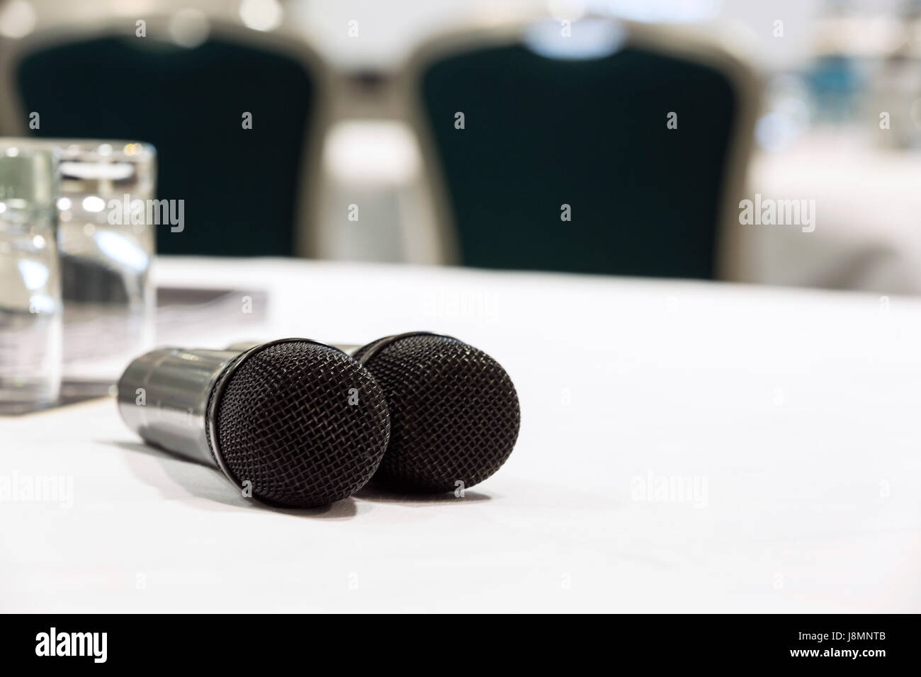 Dos micrófonos en un cuadro blanco utilizado para Q&A en una conferencia o sala de reuniones. Sillas y una pantalla en el fondo Foto de stock