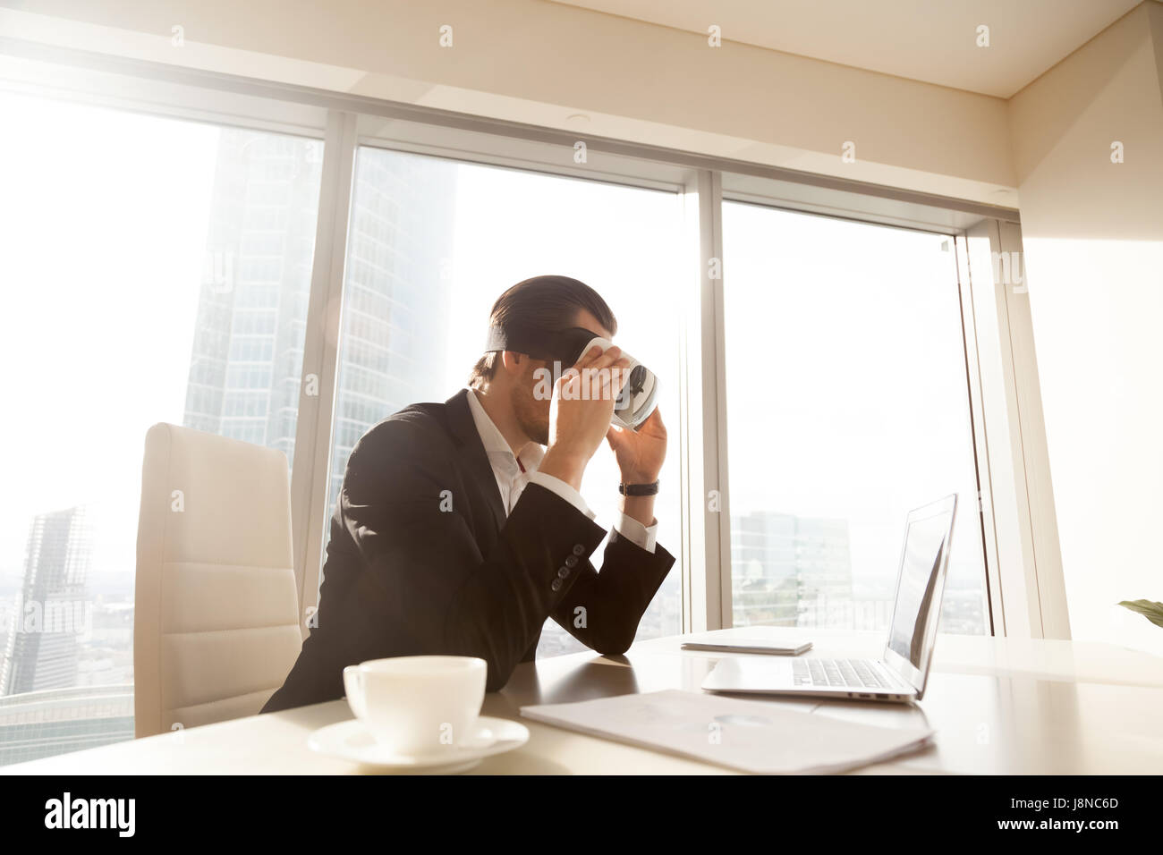 Hombre mirando la pantalla de un ordenador portátil a través de auriculares VR Foto de stock