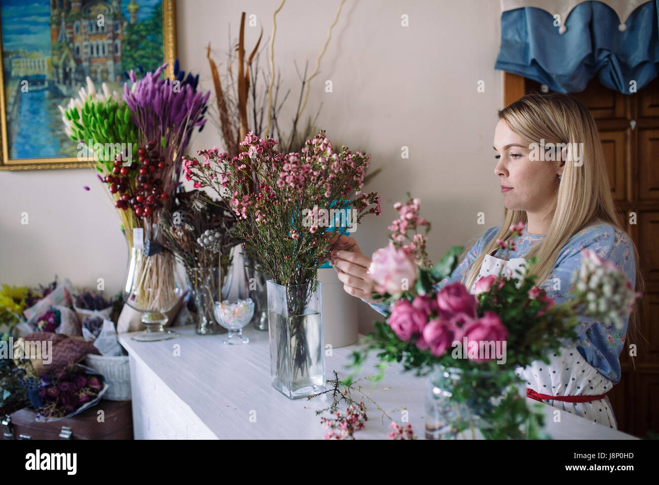 Mujer floristería haciendo ramo de flores rosas de interior. Florist hembra preparar bouquet en flower shop Foto de stock