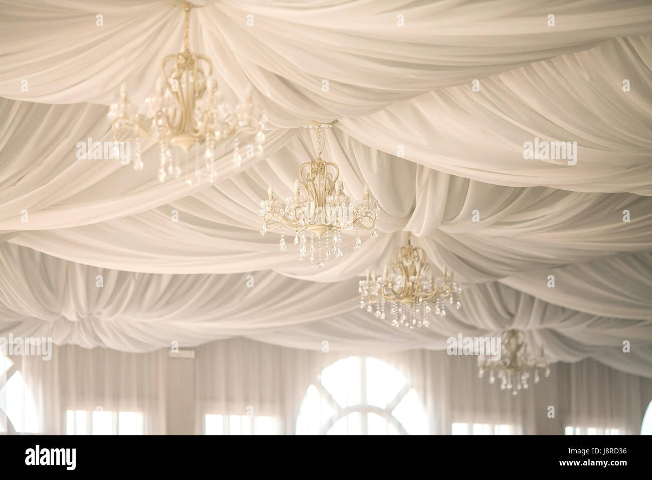 Lámparas de araña en el techo, decoradas con telas blancas sábanas. Una decoración de boda en carpa blanca Fotografía de stock - Alamy