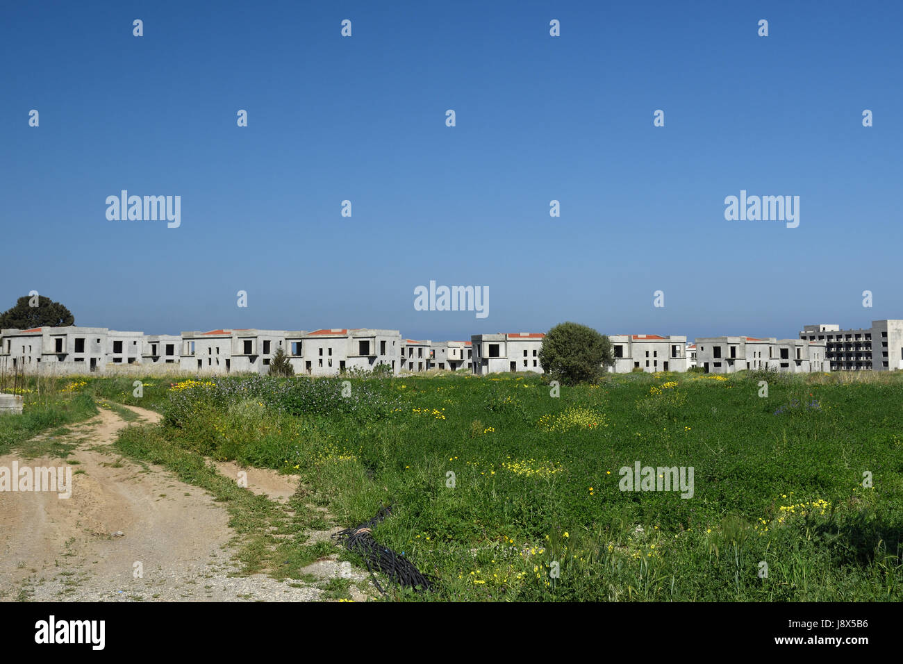 Muchas de las casas recién construidas vacía en el fondo y un cielo azul fuera de la aldea Lapta en el norte de Chipre. Foto de stock