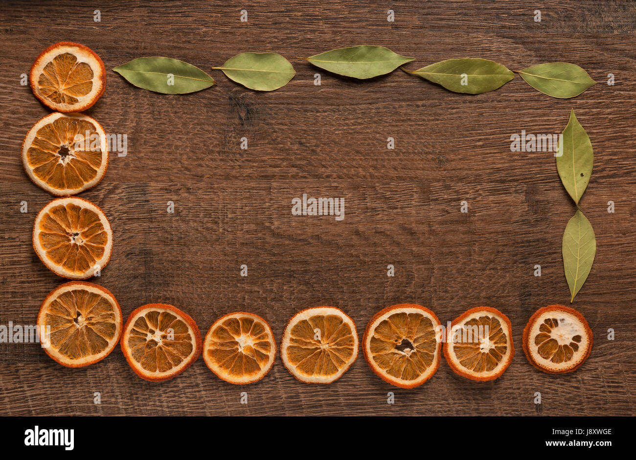 Secas de naranja y hojas de laurel en la vieja tabla de madera oscura. Vista desde arriba. Foto de stock