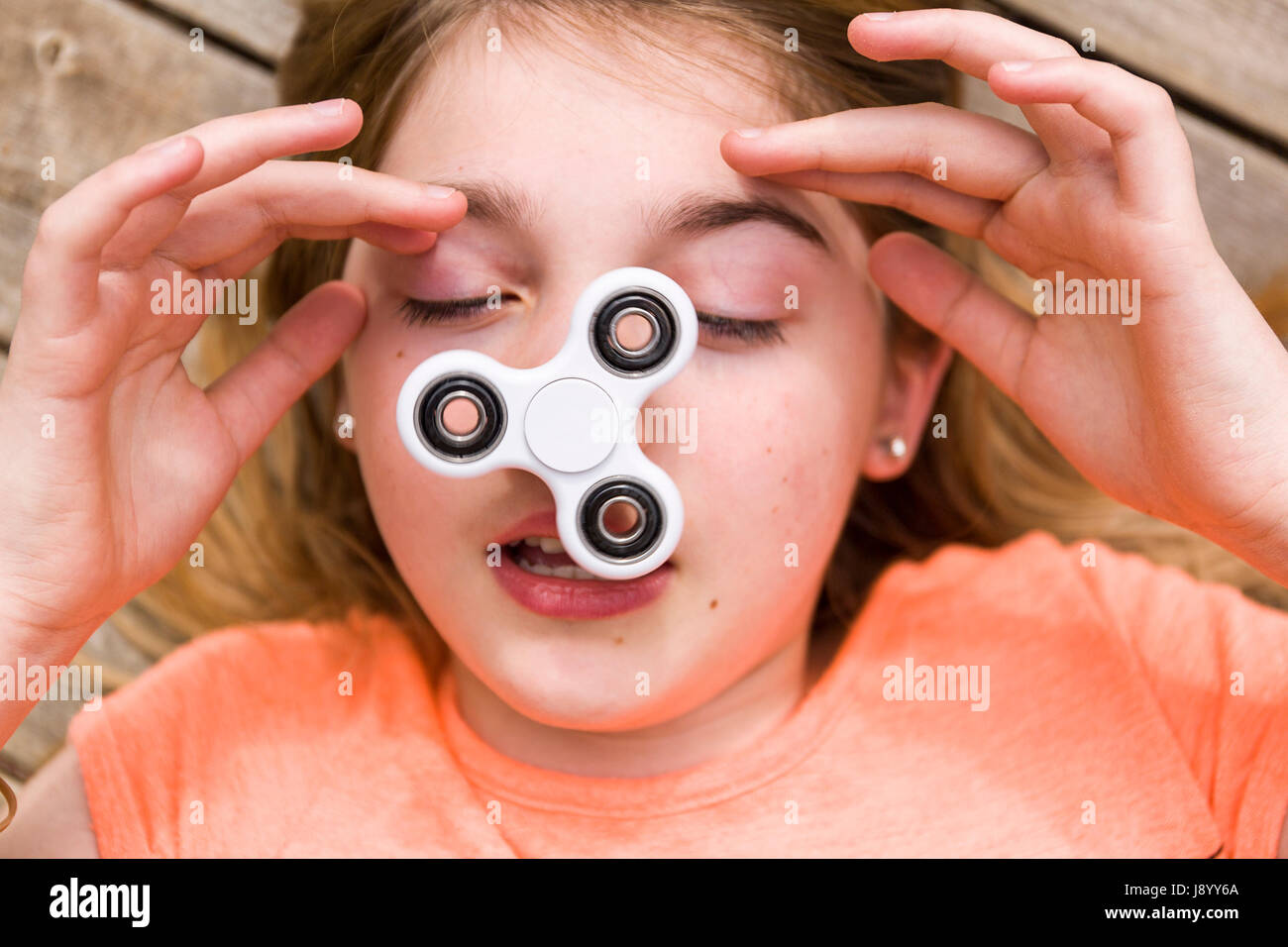 Adolescente femenina jugando con molestar spinner spinning juguete en su nariz modelo de liberación: Sí. Liberación de propiedad: No. Foto de stock