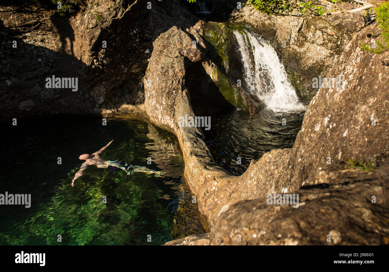 Bucear bajo un arco sumergido en el Cuento de piscinas, Cuillins, en la Isla de Skye. Una hermosa tarde soleada y cálida en Escocia. Foto de stock