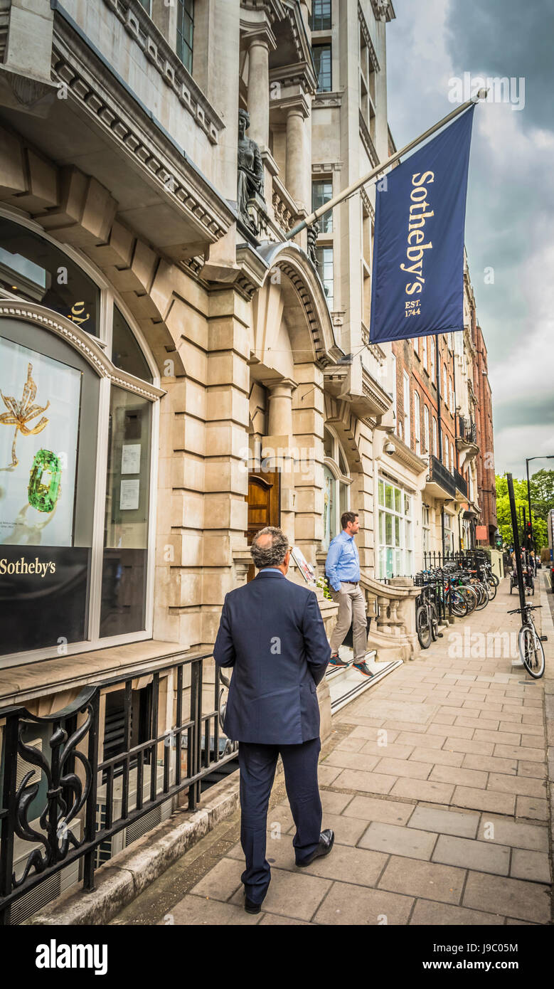 Un hombre de negocios caminando por New Bond Street en frente de Sotheby's, Mayfair, Londres, Inglaterra Reino Unido Foto de stock