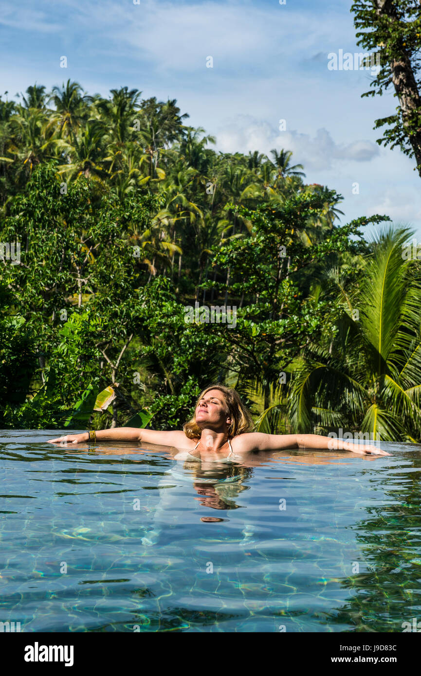 La mujer disfruta de una piscina desbordante por encima de un valle en el Kamandalu Resort Ubud, en Ubud, Bali, Indonesia, Sudeste Asiático, Asia Foto de stock