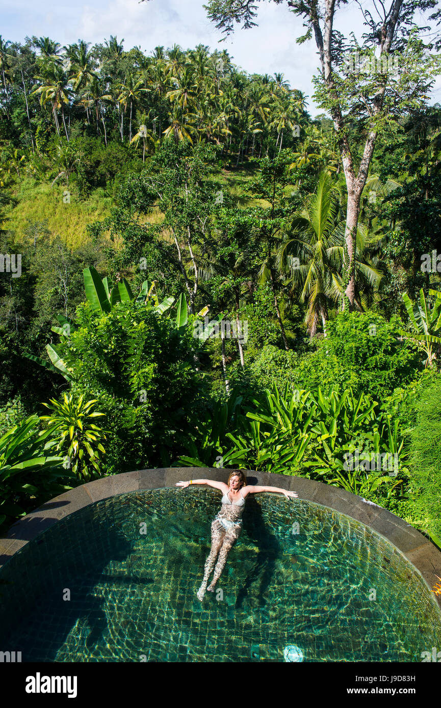 La mujer disfruta de una piscina desbordante por encima de un valle en el Kamandalu Resort Ubud, en Ubud, Bali, Indonesia, Sudeste Asiático, Asia Foto de stock