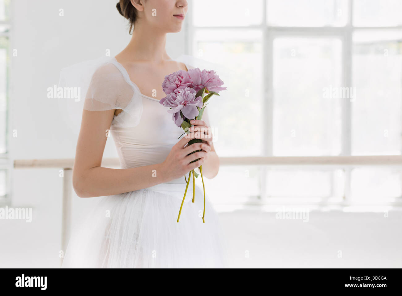 Increíblemente hermosa y joven bailarina está posando y bailando en un estudio blanco Foto de stock