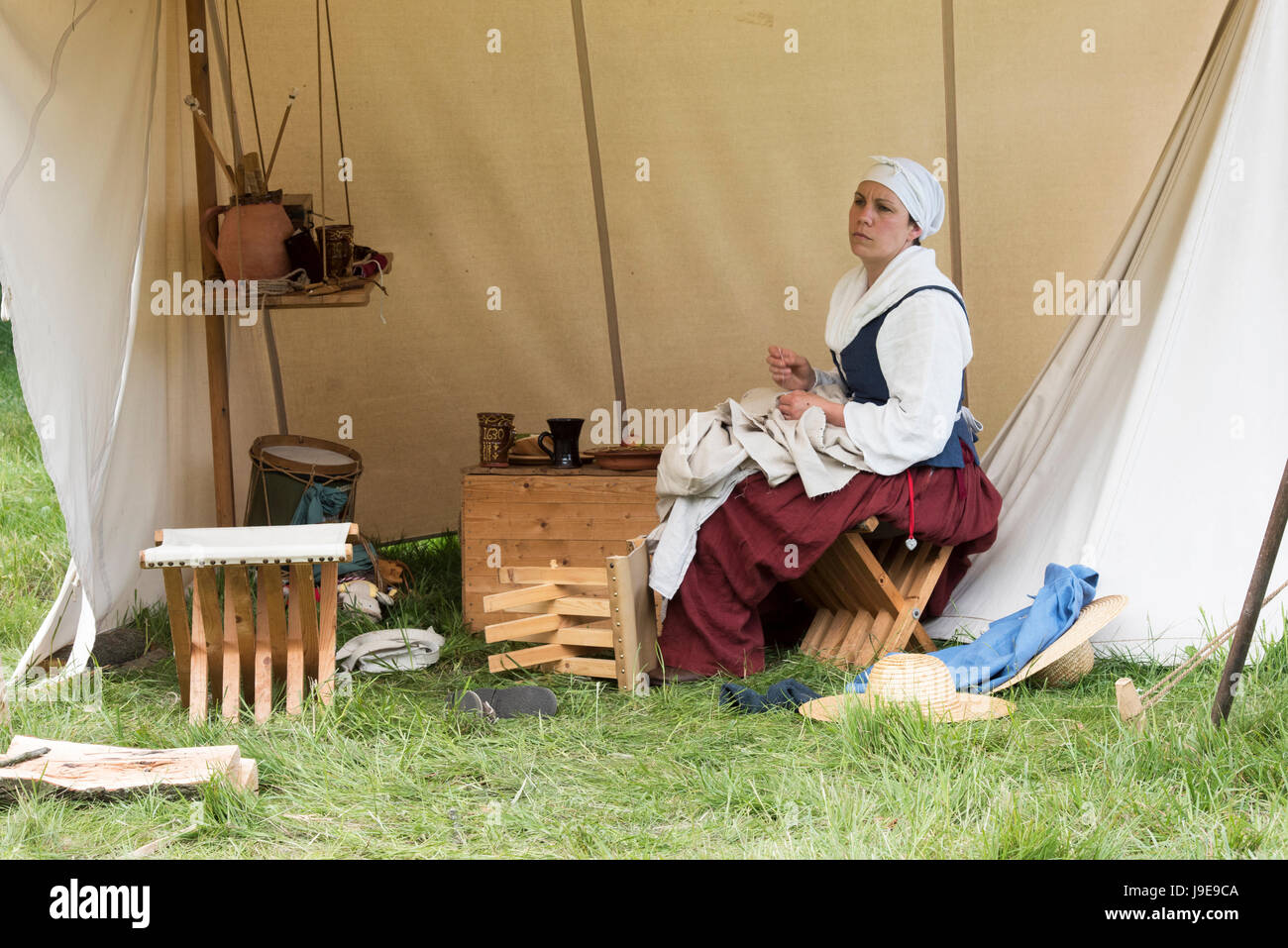 Mujer cosiendo una camisa en un campamento en un nudo sellado guerra civil inglesa recreación evento. Charlton Park, Malmesbury, Wiltshire, UK Foto de stock