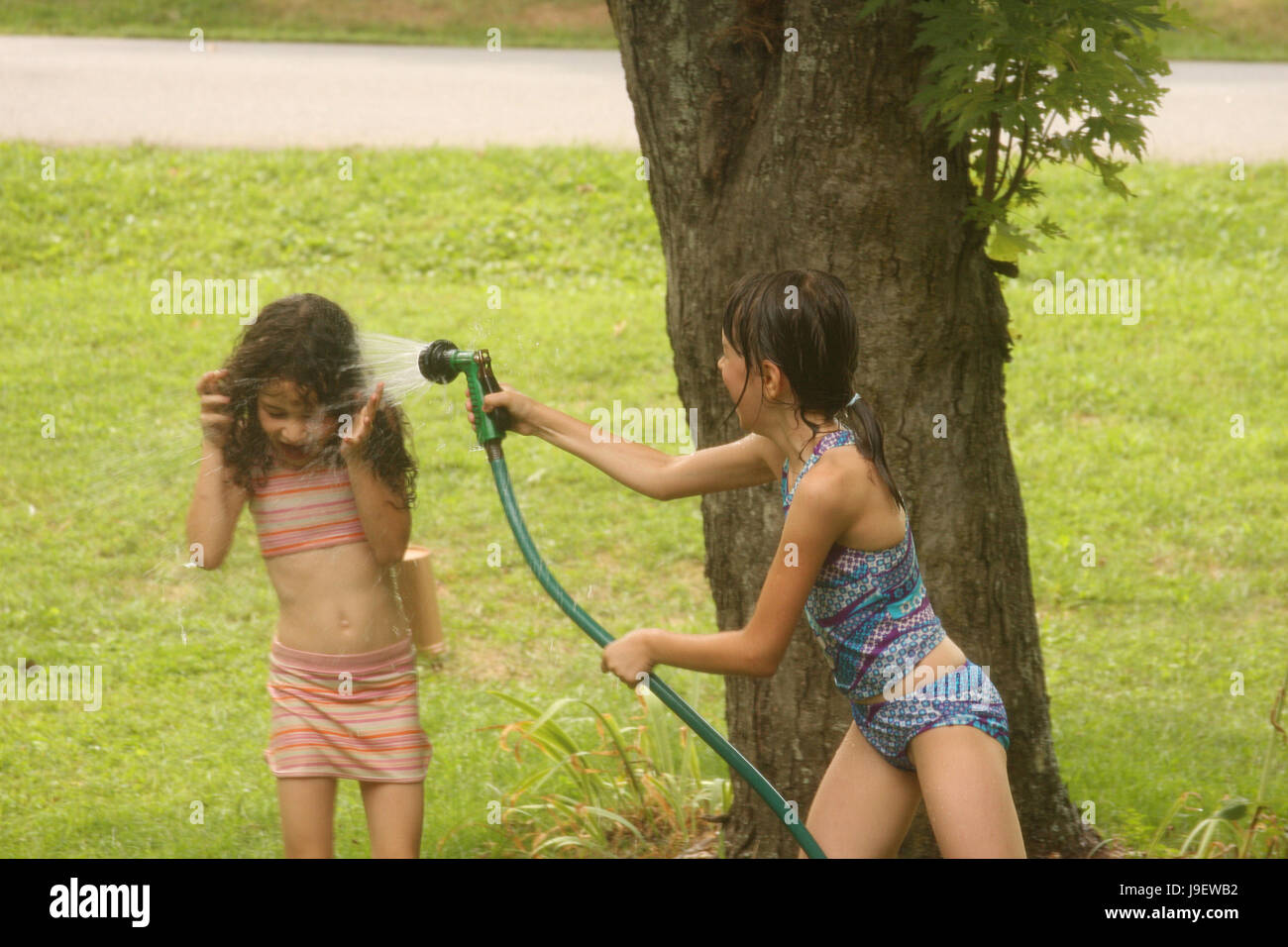 Dos niñas jugando con el agua de la manguera en el día de verano Fotografía  de stock - Alamy
