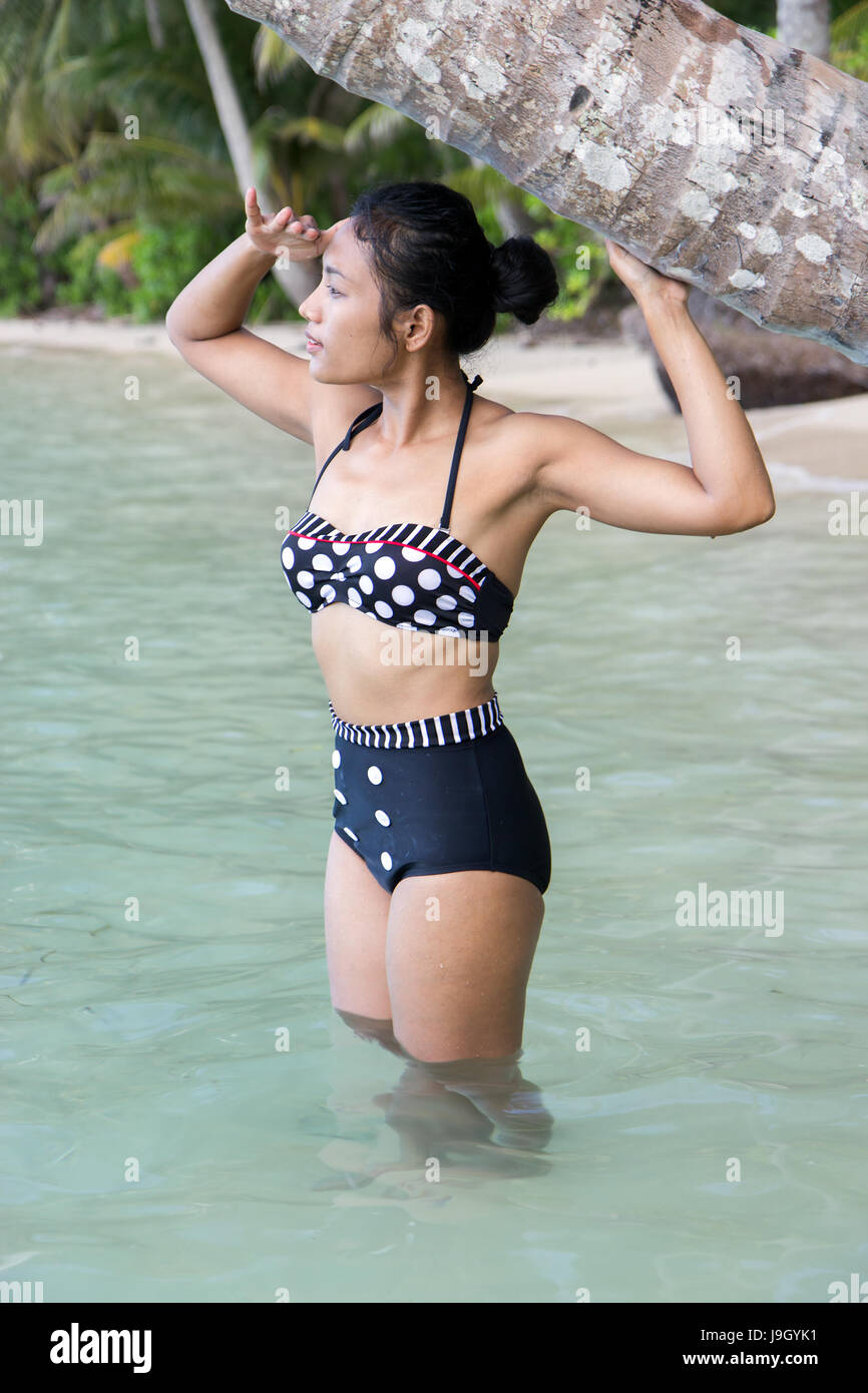 Mujer atractiva en bañador retro de pie en el mar transparente. Hermosa  muchacha asiática en la historia de la moda vestido de baño relajado en una  isla tropical Fotografía de stock -