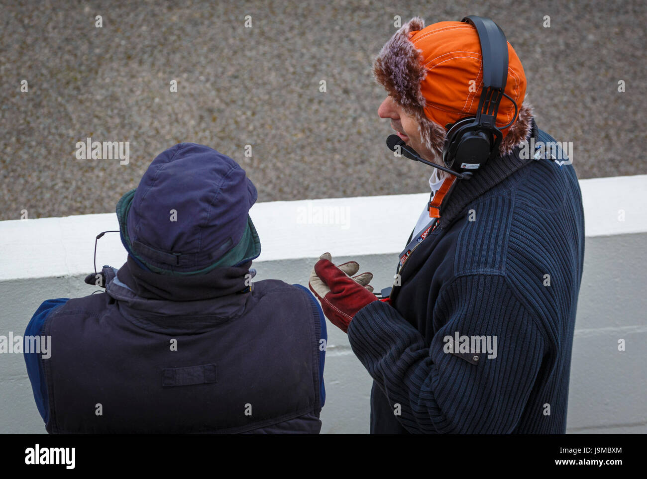 Dos pit marshalls, usando auriculares y micrófonos, en discusión en el Goodwood GRRC 74a reunión de miembros, Sussex, Reino Unido. Foto de stock