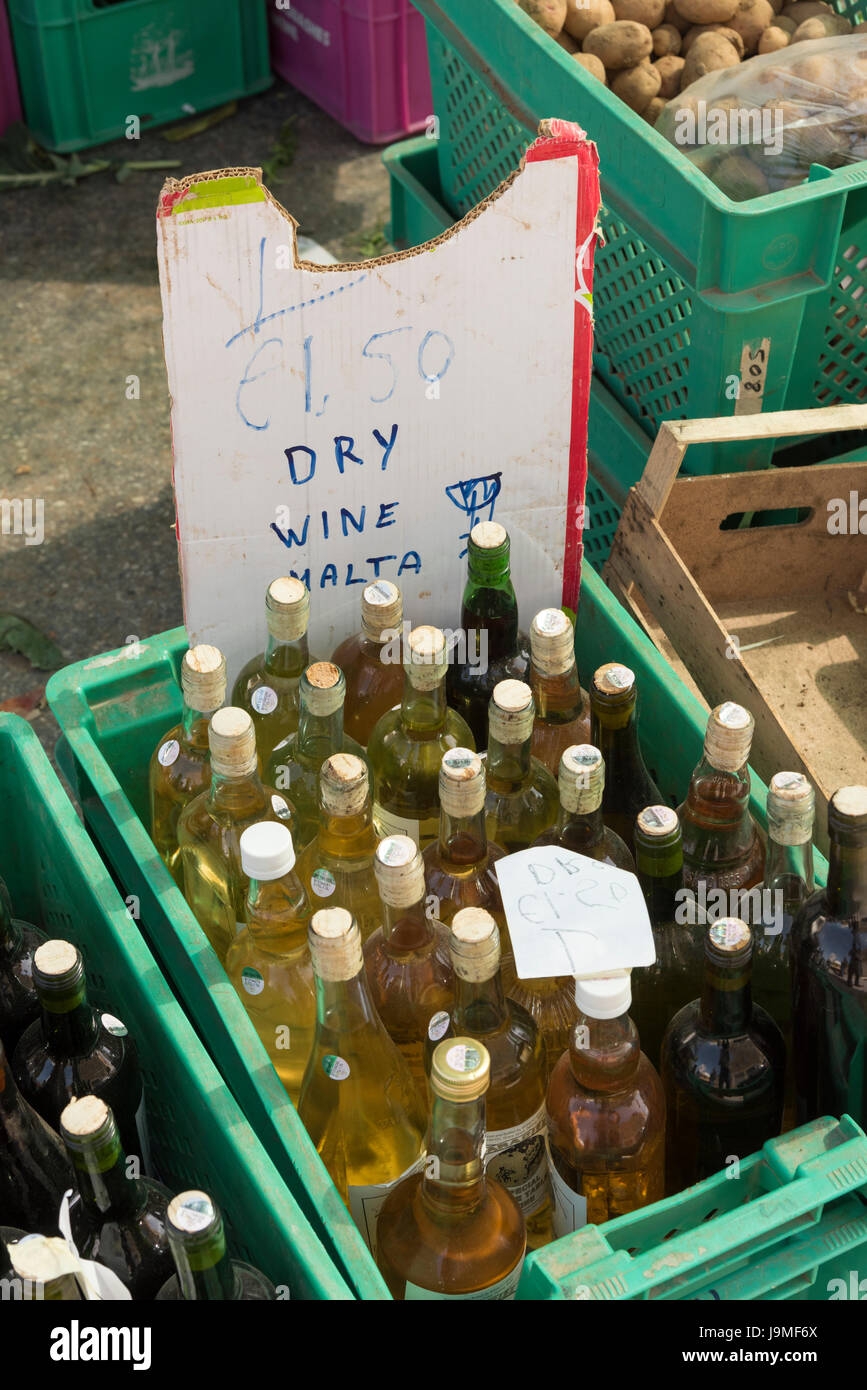 Botellas de vino blanco seco a la venta en una caja en un puesto en el mercado de Marsaxlokk, Malta. Rústica con un signo casero Foto de stock