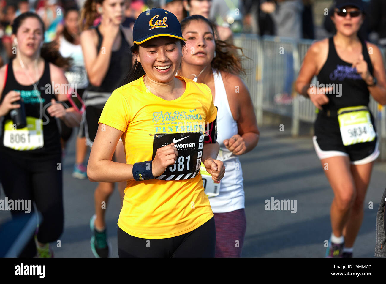 Asia sonriente Atleta Femenina acercándose a la línea de meta en la media maratón de la mujer Nike, San Francisco. Foto de stock