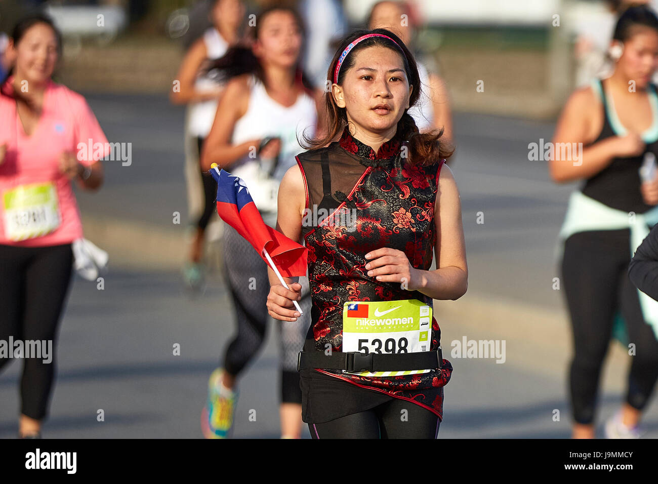 La atleta femenina asiática acercándose a la línea de meta en la media maratón de la mujer Nike, San Francisco. Foto de stock