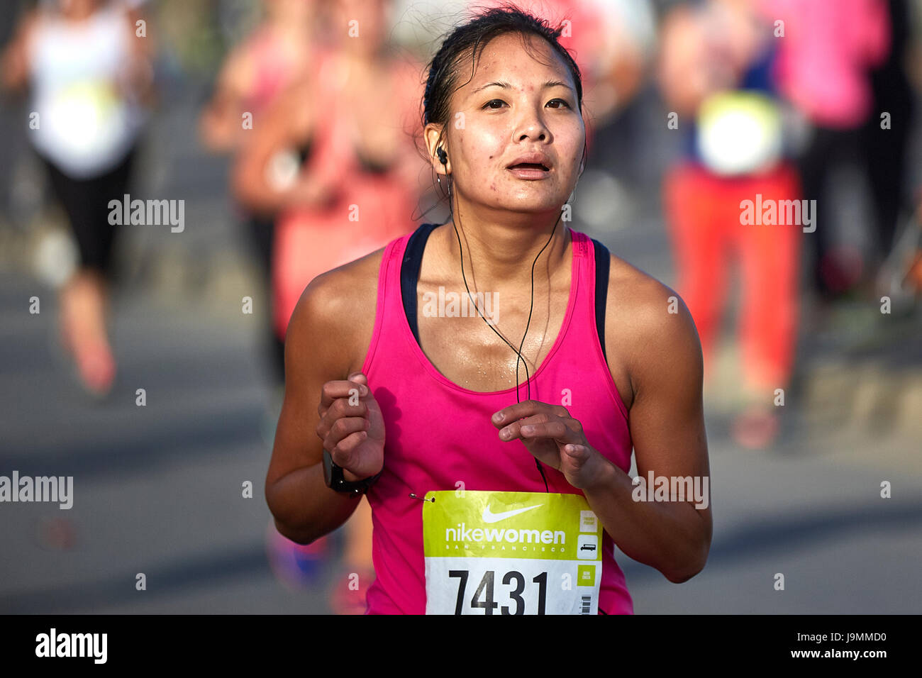 Determina la atleta femenina asiática acercándose a la línea de meta en la media maratón de la mujer Nike, San Francisco. Foto de stock