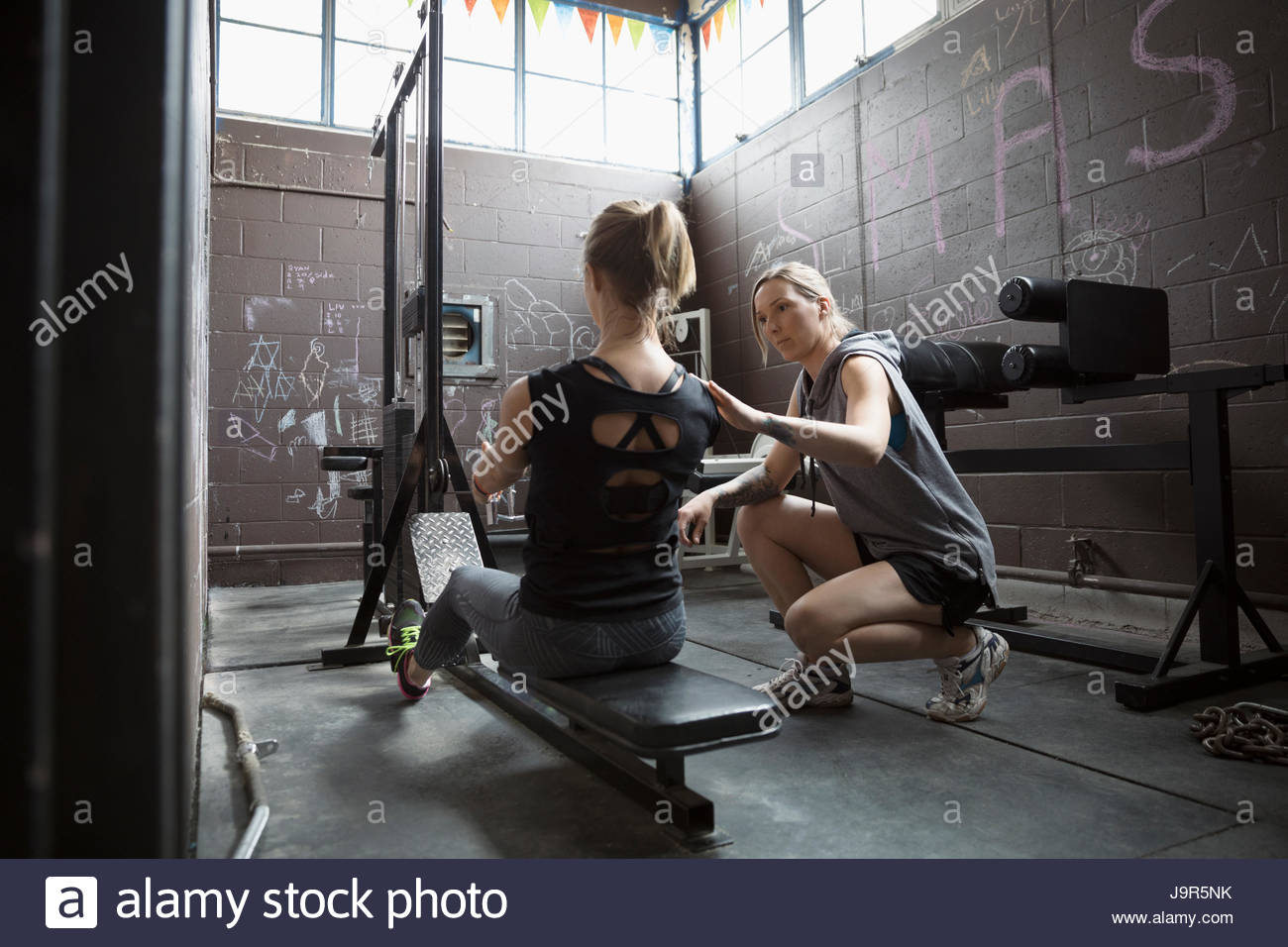 Entrenador Personal mujer rector el levantamiento de pesas, haciendo sentados en filas cochambroso gimnasio Foto de stock