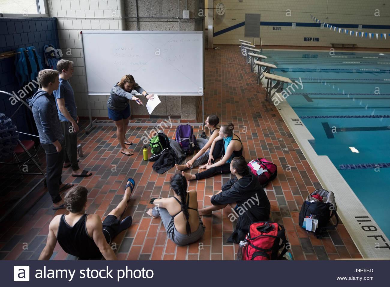 Carrera de coaching coach femenina al equipo de natación en la piscina práctica Foto de stock