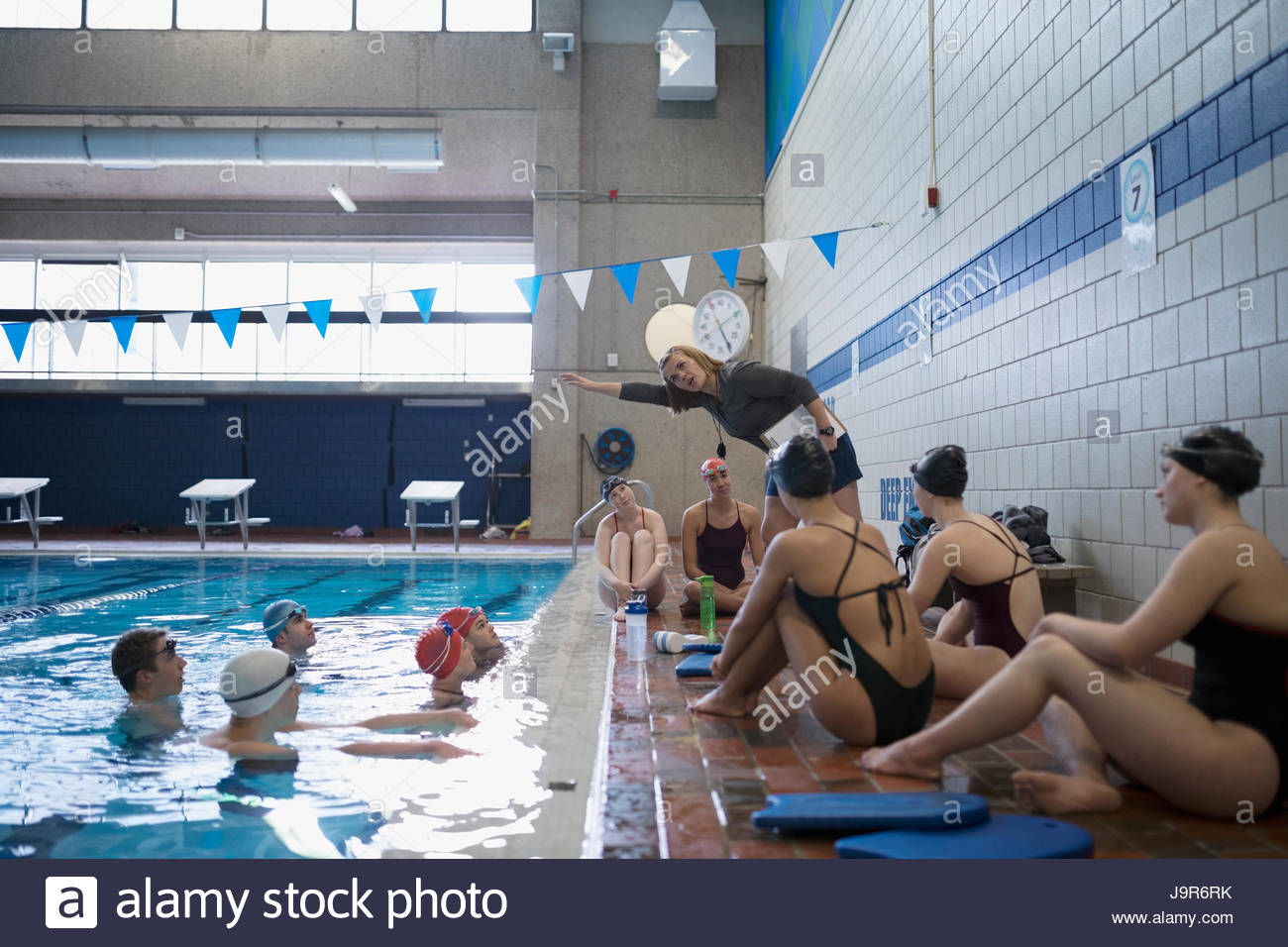 Entrenador femenino explicando trazo para nadadores en piscina en la práctica Foto de stock