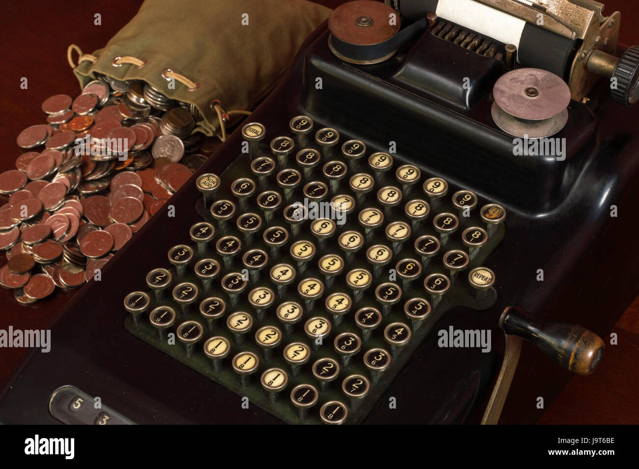 Black Antique calculadora con botones pulsadores mecánicos y una bolsa de monedas junto a ella. Foto de stock
