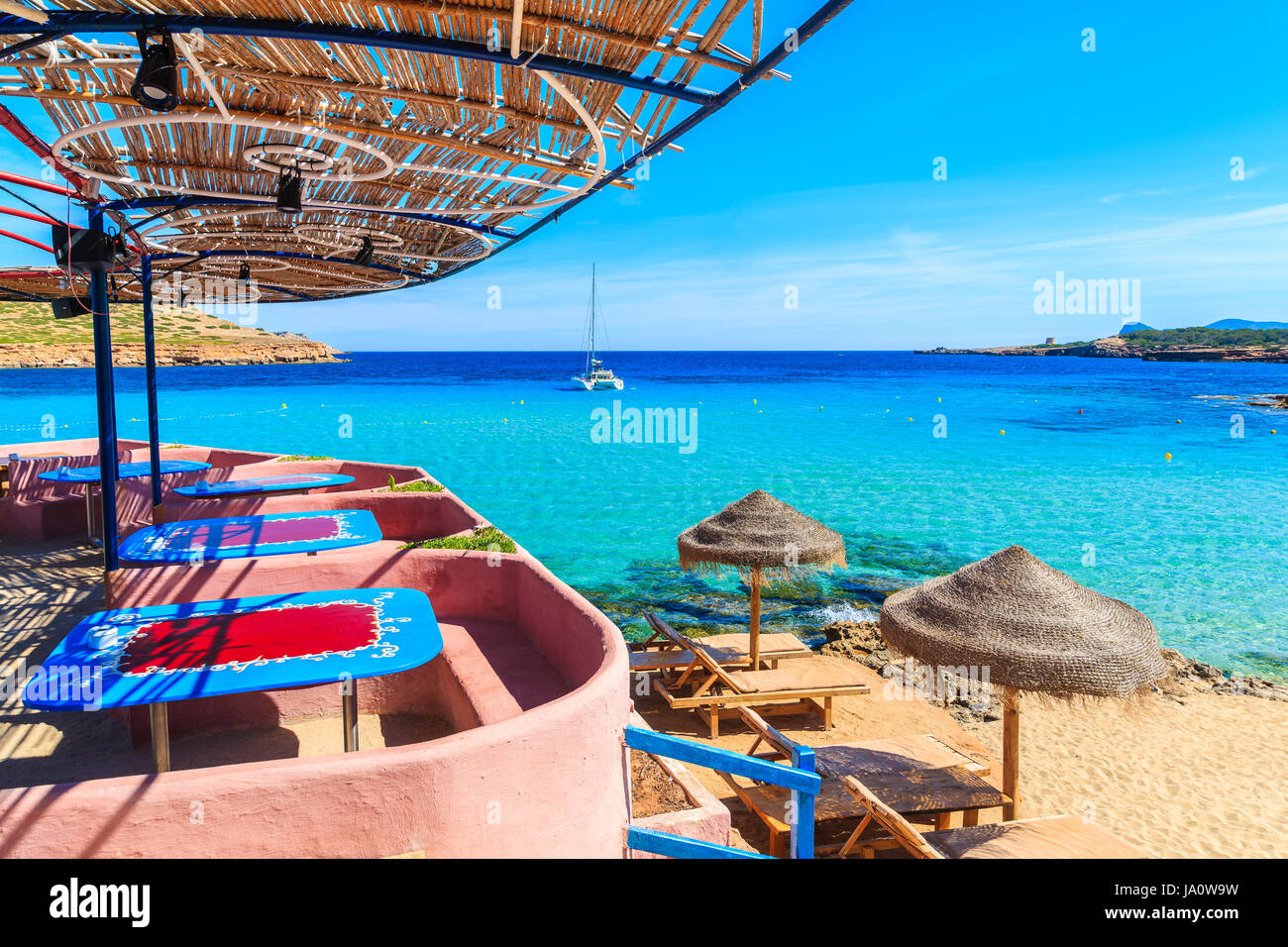 Vista de la playa de Cala Comte con hamacas y sombrillas en la costa, la isla de Ibiza, España Foto de stock