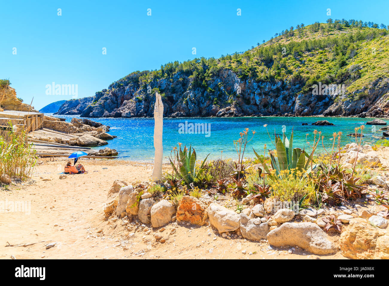 Par de personas no identificadas en la recluida para tomar el sol Cala d'en Serra, en la playa de la isla de Ibiza, España Foto de stock