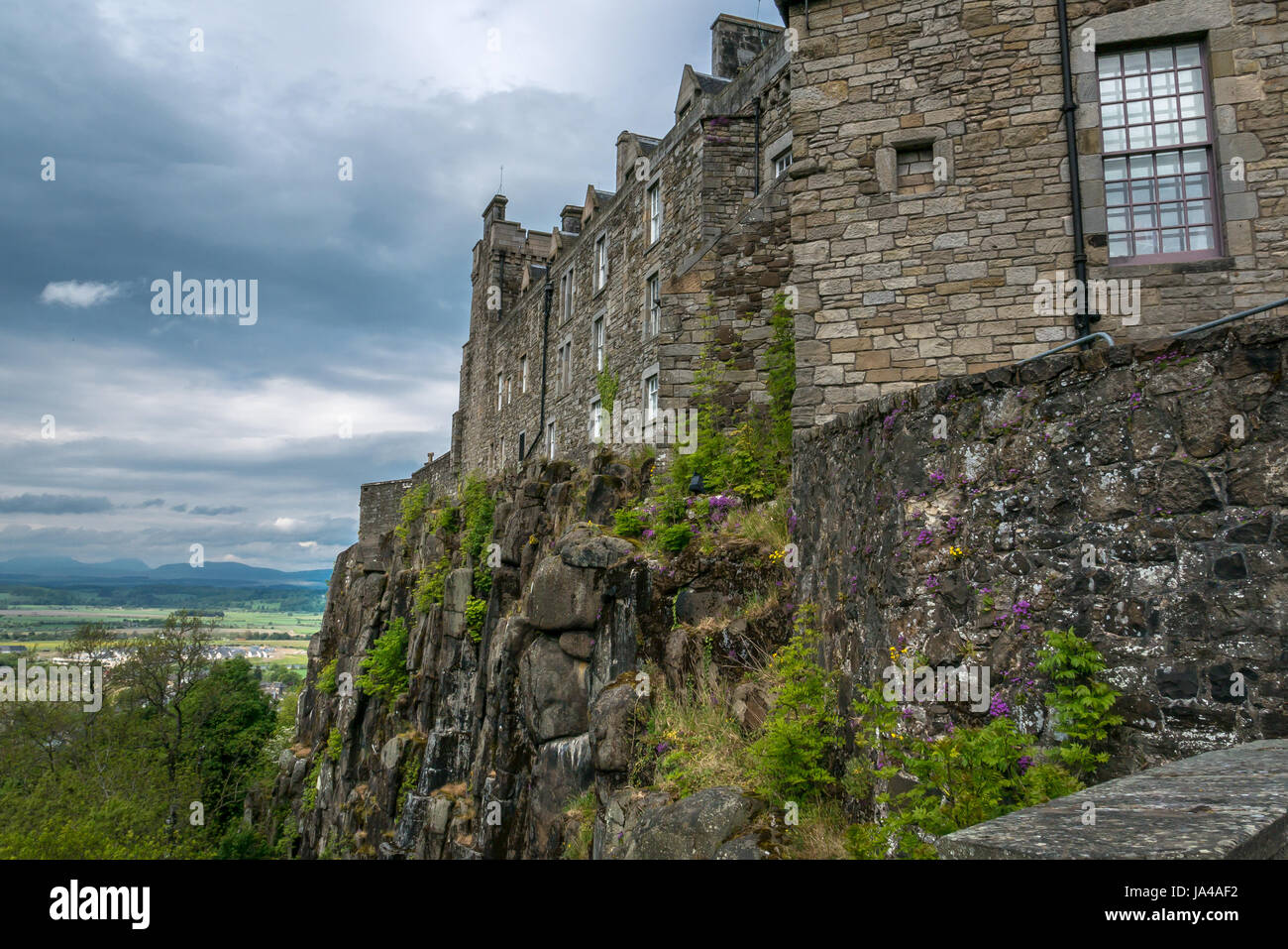 Vista de afloramiento rocoso acantilado con la muralla del castillo de Stirling y el paisaje lejano más carse de Stirling, con el cielo gris de Moody, Stirling, Escocia, Reino Unido Foto de stock