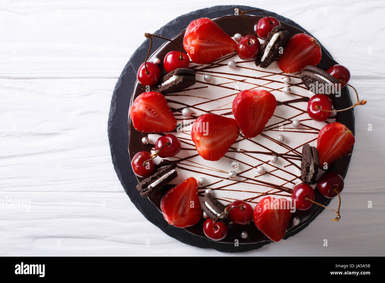 Festivo tarta de chocolate con fresa y cereza de cerca en la tabla vista desde arriba de la horizontal. Foto de stock