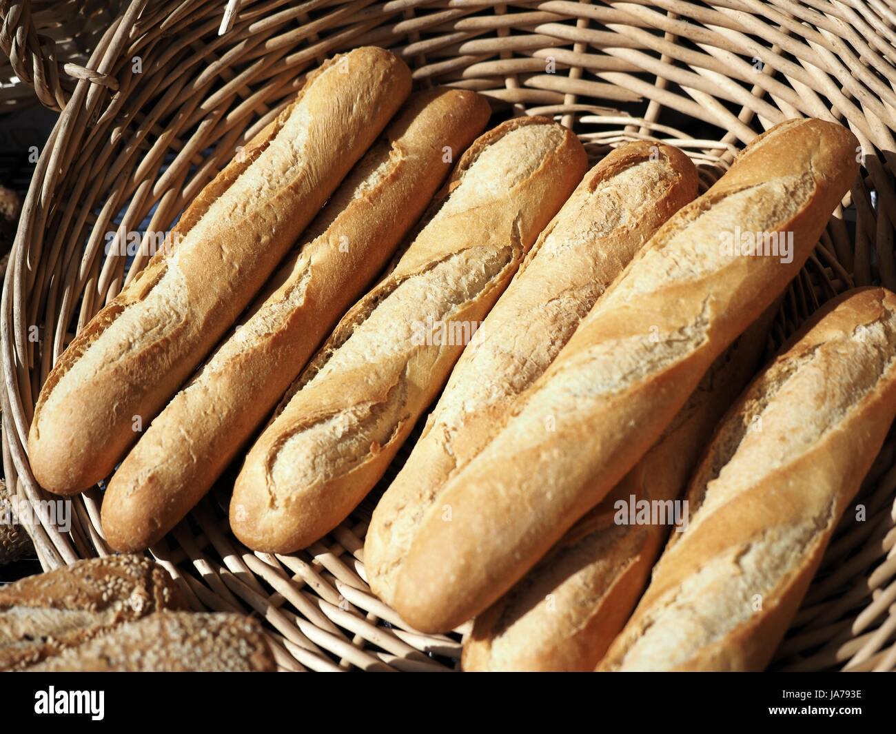 Algunas de las baguettes en una cesta de mimbre, fresco y fragante, sabroso, cálido crujiente pan francés Foto de stock