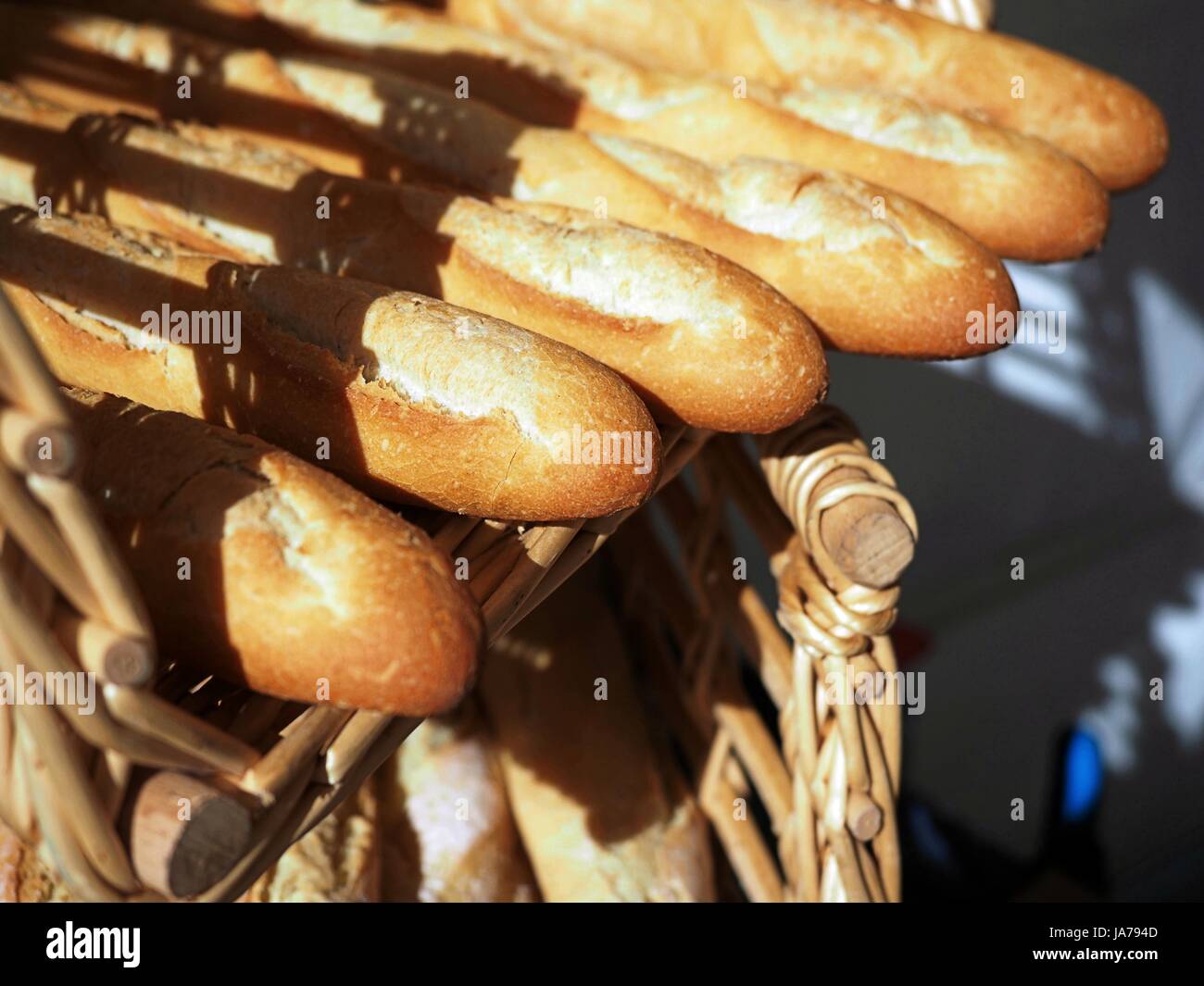 Algunas de las baguettes en una cesta de mimbre, fresco y fragante, sabroso, cálido crujiente pan francés Foto de stock