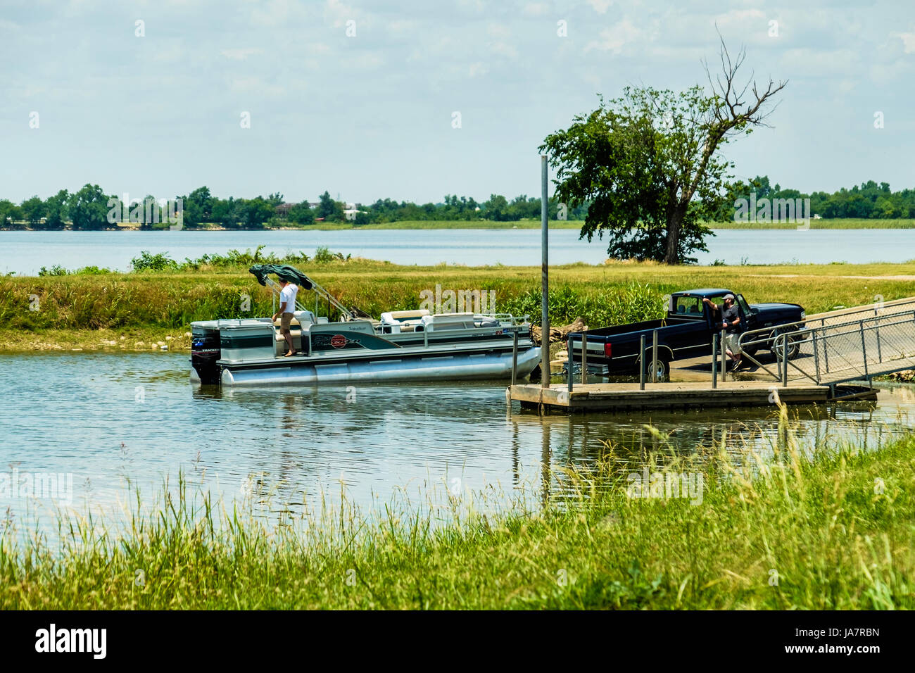 Dos hombres cargan un Pontoon Boat en un barco remolque después de la pesca en el lago Overholser en Oklahoma City, Oklahoma, Estados Unidos. Foto de stock
