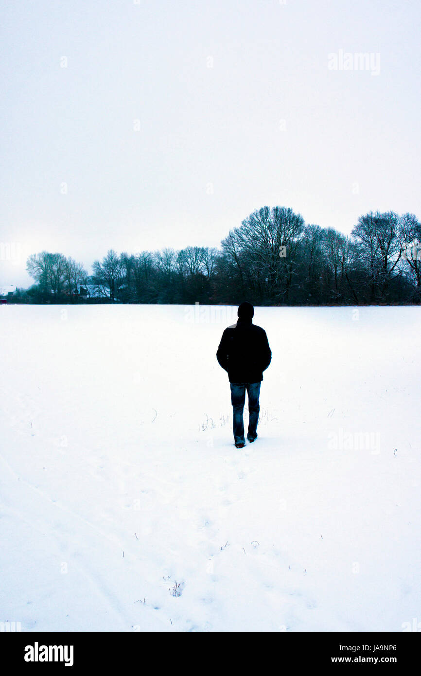 Hombre caminando en un campo cubierto de nieve Foto de stock