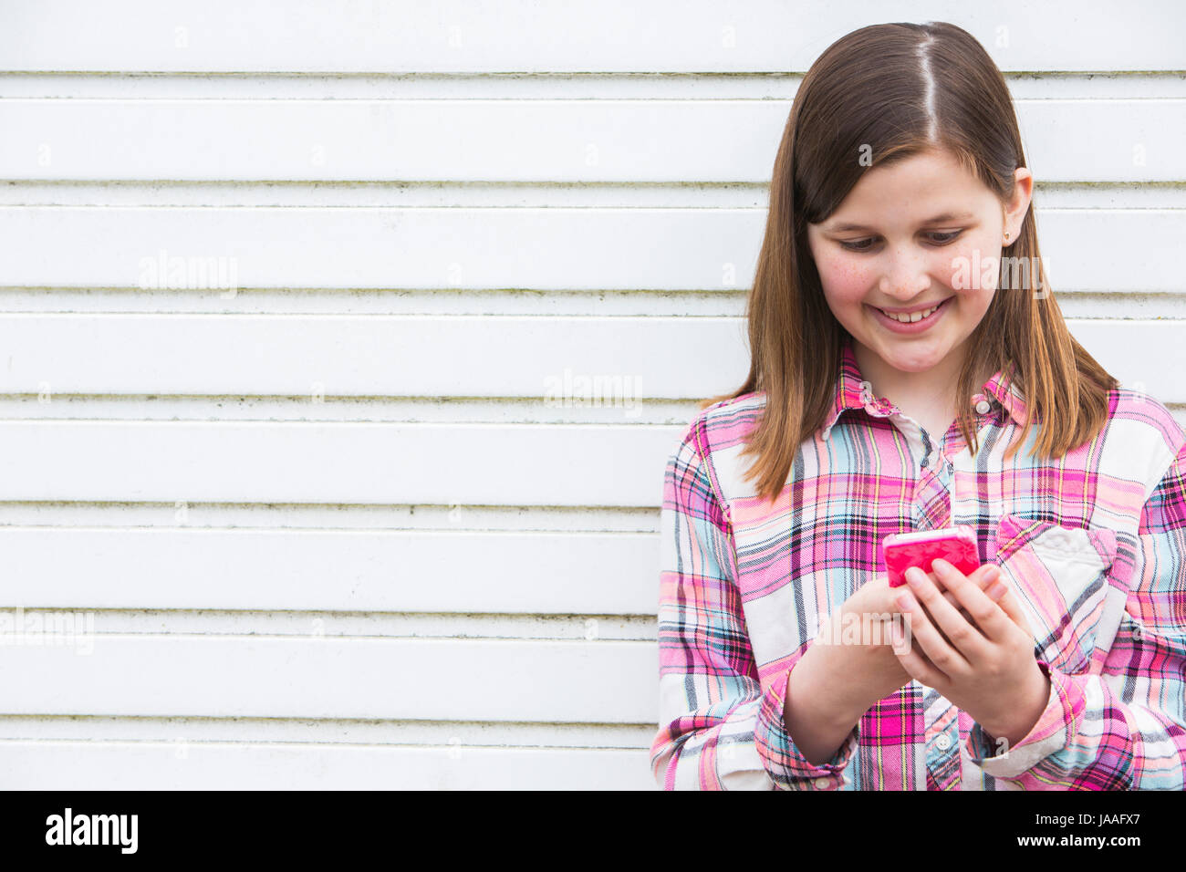 Pre Teen Girl mensajes de texto en un teléfono móvil en el entorno urbano Foto de stock