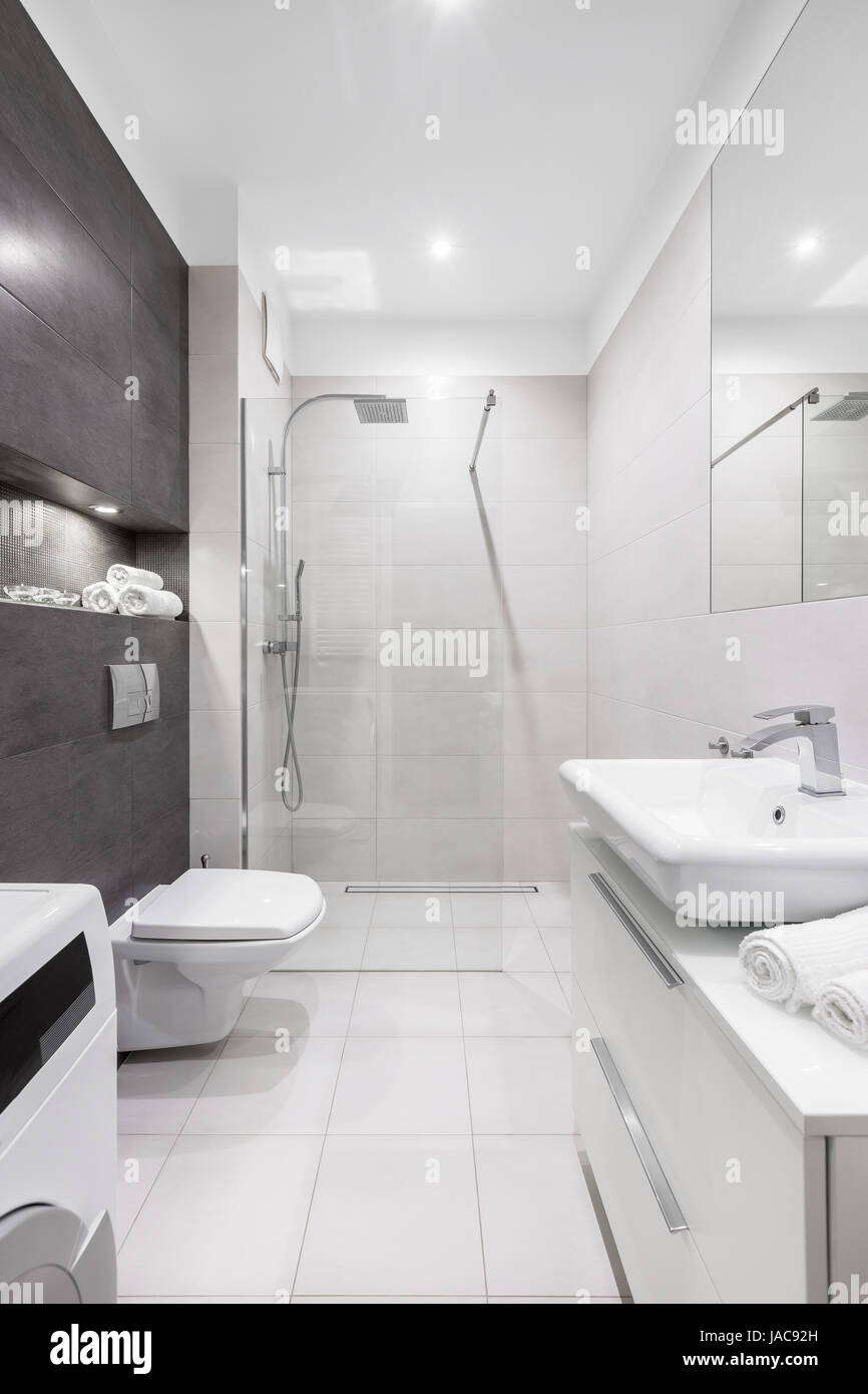 Blanco y moderno cuarto de baño con ducha, inodoro, lavabo y pared oscura  Fotografía de stock - Alamy