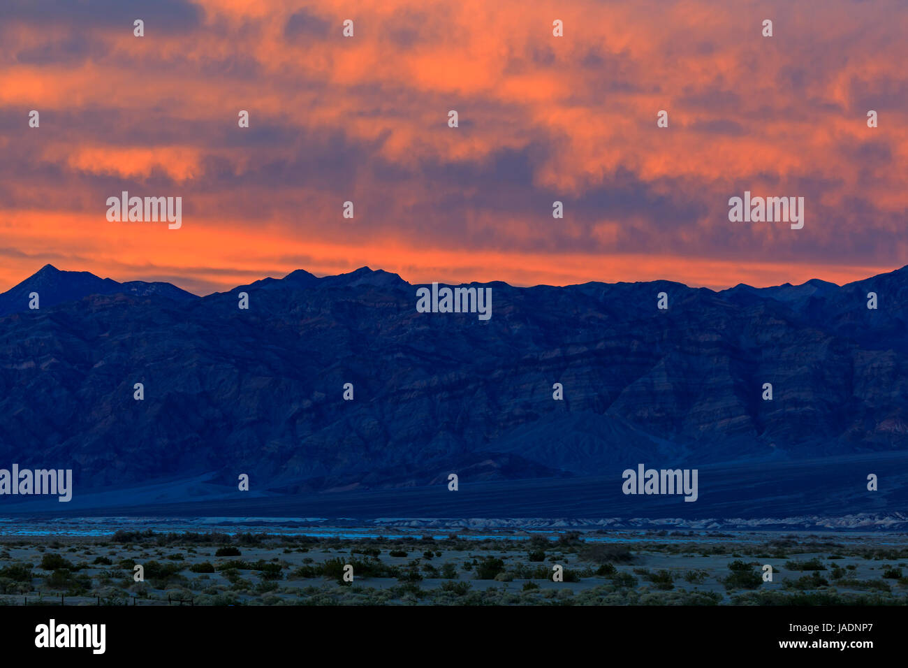 En esta foto la posluminiscencia del atardecer ilumina las nubes sobre el rango de Panamint, en el lado oeste del Parque Nacional Valle de la Muerte, California, Estados Unidos. Foto de stock
