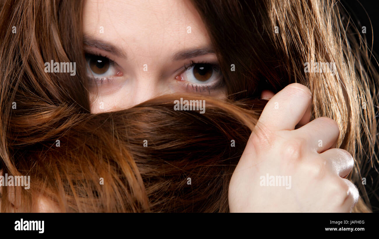 Close-up retrato de una bella mujer cubre el rostro por largos pelos marrones Foto de stock