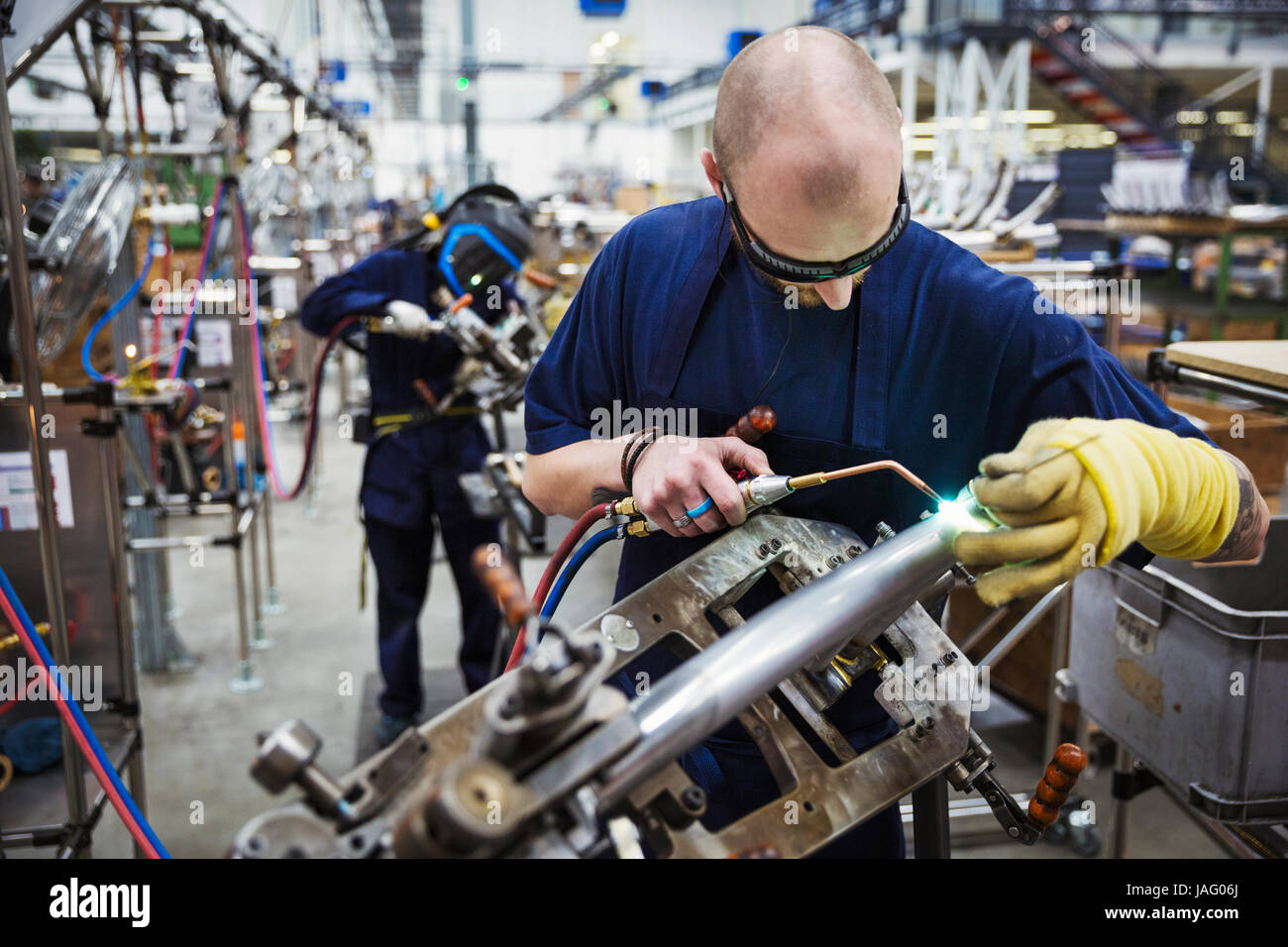 Macho obrero cualificado llevar gafas protectoras, usando una herramienta  de soldadura, trabajando sobre una bicicleta en una fábrica Fotografía de  stock - Alamy