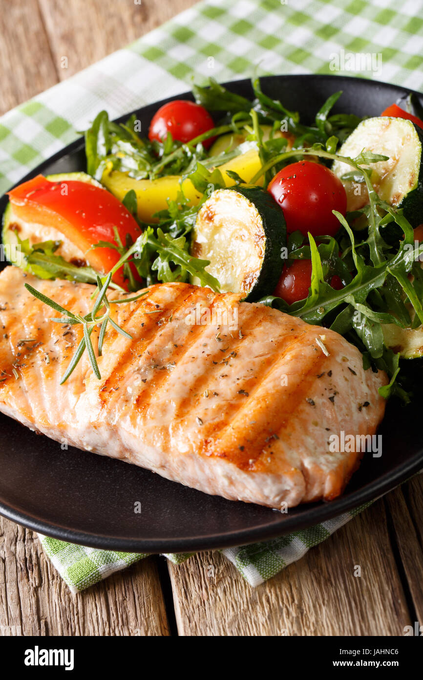 Alimentos dietéticos: Salmón a la plancha y ensalada de verduras con rúcula  closeup en una placa vertical Fotografía de stock - Alamy