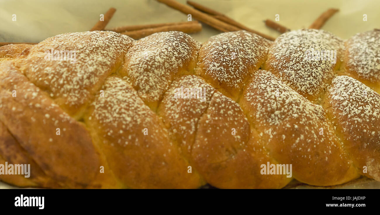 Alimentos cocinados frescos, una delicia crujiente pan de canela trenzado twist espolvoreado con azúcar glas Foto de stock