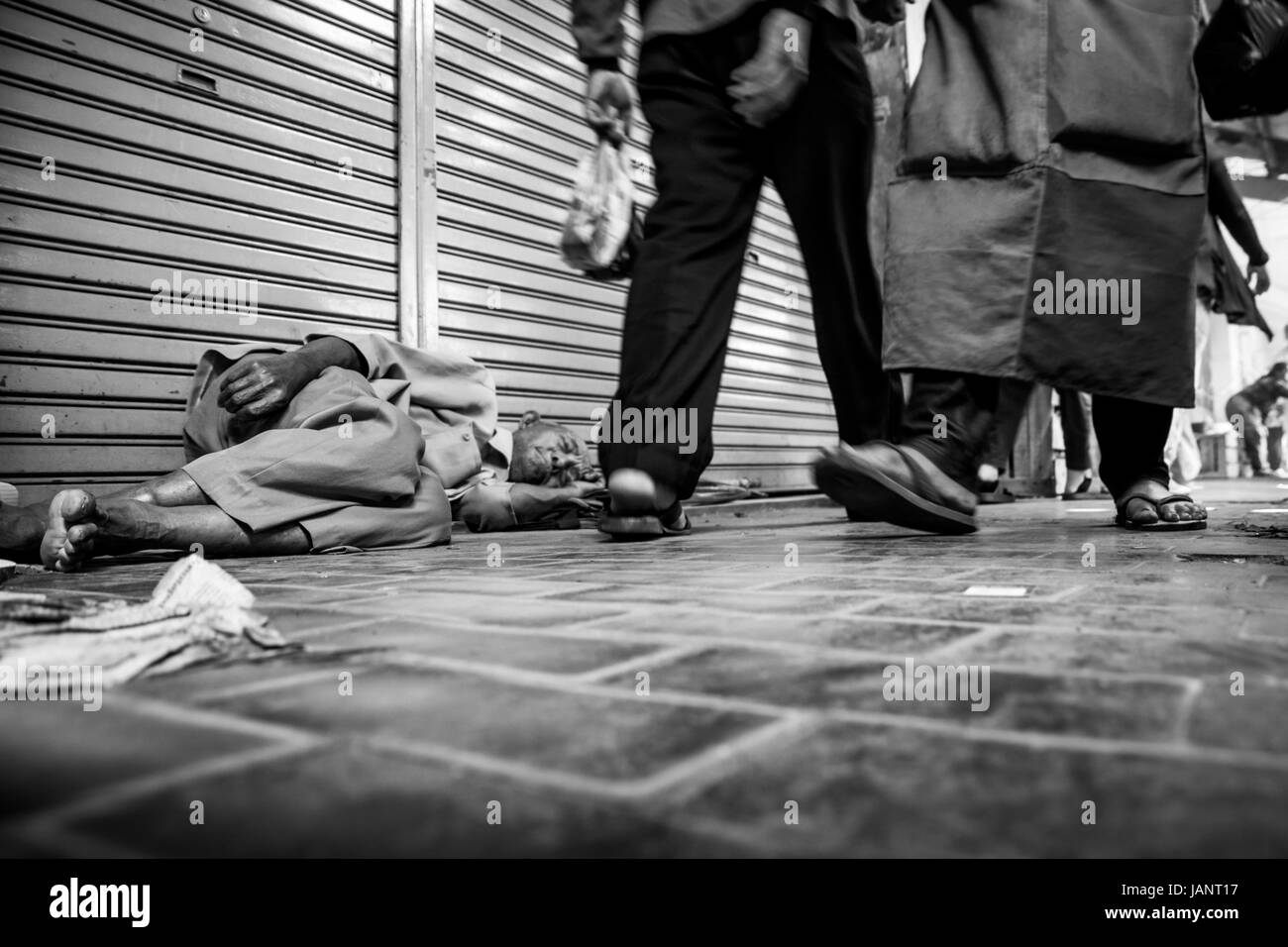 Hombre sin hogar durmiendo en las calles de la ciudad en Indonesia. Reportaje en blanco y negro La imagen de la gente que pasaba indiferente viejo hombre durmiendo en la calle Foto de stock