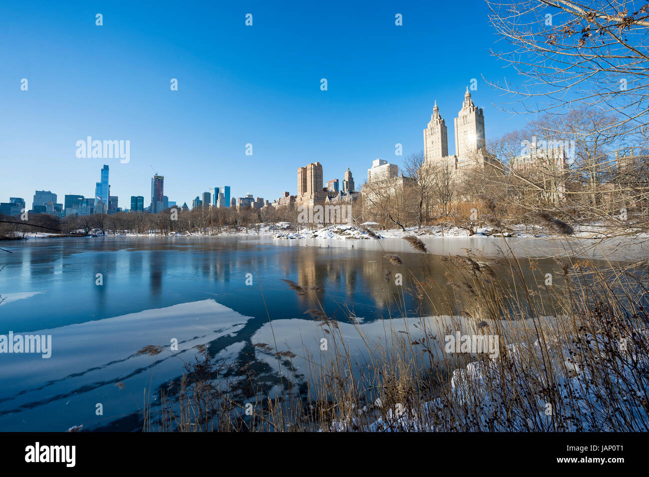 Vista panorámica de la Upper West Side skyline reflejando en el hielo del parque central del lago congelado después de una tormenta de nieve de invierno en la Ciudad de Nueva York Foto de stock