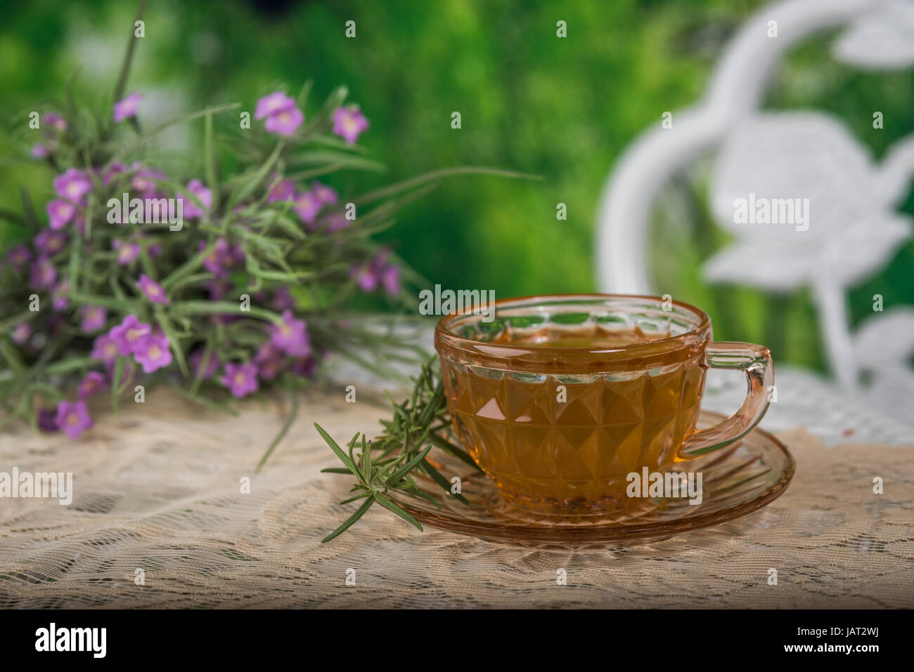 Taza de té blanco sentado en una mesa al aire libre con un ramo de flores Foto de stock