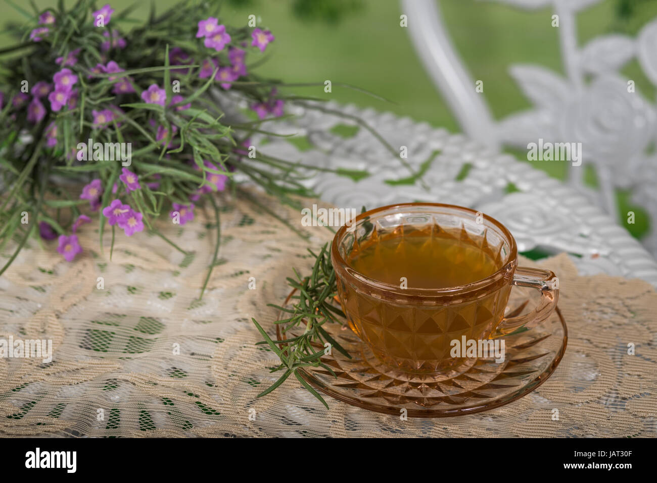 Taza de té blanco sentado en una mesa al aire libre con un ramo de flores Foto de stock