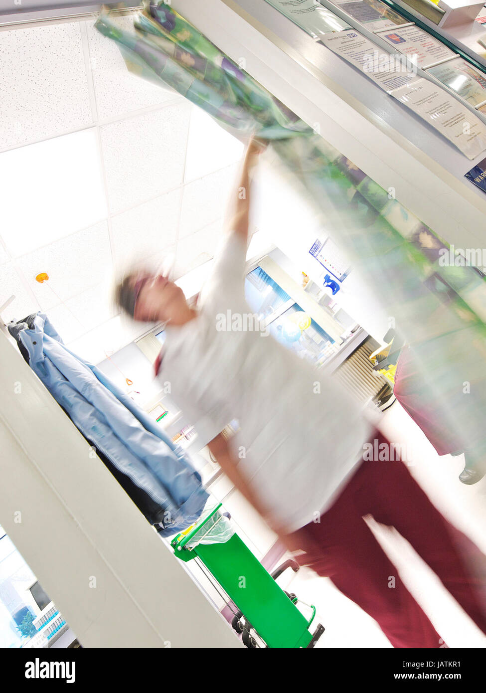 Healthcare NHS asistente o enfermera retrocede un cubículo cortina de post-tratamiento de un paciente en un hospital del Reino Unido Foto de stock