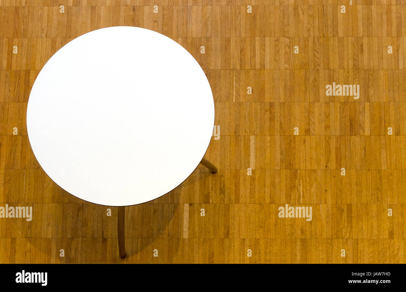 Blick von oben auf Tisch mit kreisförmiger weißer Tischplatte und Parkettboden; vista desde arriba en la tabla circular de color blanco con tablero y piso de parquet Foto de stock